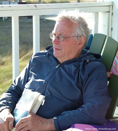 elderly man relaxing on deck chair with a book in his lap