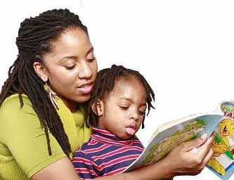 mother holds book and reads over the shoulder of young toddler